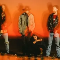 Los miembros de Alice in Chains posan con un fondo naranja vibrante.