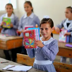 Niña sonriente con cuadernos coloridos en una escuela de Ámsterdam.