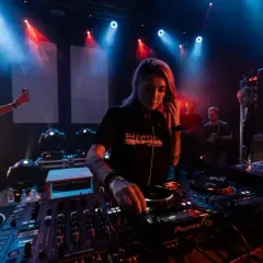 DJ Nusha que es, concentrada en la mesa de mezclas, rodeada de luces y público.