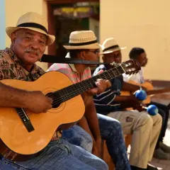 Son cubano cantantes, con guitarras y maracas, crean música alegre bajo el sol.