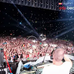 Multitud vibrante en una EDP beach party, con confeti cayendo y luces iluminando la noche.