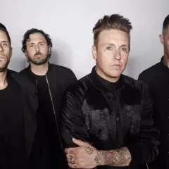Los miembros de Papa Roach posan juntos, vestidos de negro, con miradas intensas.