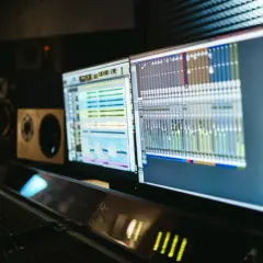 Monitores con software de producción electrónica y mesa de mezclas en un estudio de sonido.