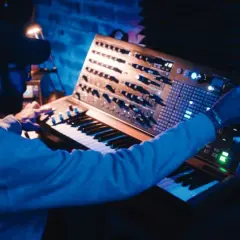 Hombre creando una compleja estructura de música electrónica en un sintetizador modular.