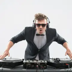 DJ con traje y auriculares, listo para mezclar. Aprende como entrar en una agencia de DJ y triunfar en la música.