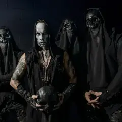 Cuatro figuras encapuchadas, con máscaras de calavera y maquillaje facial pálido, posan sombríamente. El líder sostiene un cráneo, evocando la estética de grupos black metal.