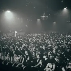 Multitud vibrante disfrutando de la techno musica en un club con luces tenues y una bola de discoteca giratoria.