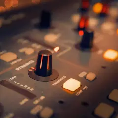 Perillas y botones iluminados en una consola de sonido, creando una atmósfera de mezcla de música.