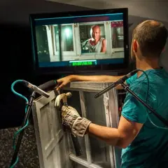 Un técnico de sonido crea efectos de **foley que es** el arte de añadir sonidos a una película, golpeando una ventana con un martillo.