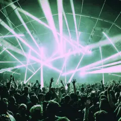 Una multitud celebra bajo un espectáculo de luces láser, un momento cumbre en la historia de la música electrónica.