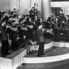 Una big band de jazz en pleno concierto, con músicos tocando trompetas, trombones, saxofones y contrabajo. ¡Pura energía musical!