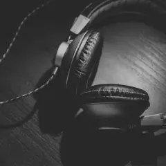 Auriculares negros sobre una superficie de madera, con un juego de luces y sombras que crea un efecto Haas.
