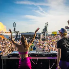 Dos DJs en un escenario lanzan fuego al aire ante una multitud masiva en uno de los festivales techno de Europa.