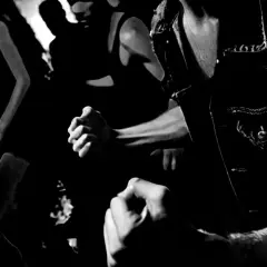 Gente bailando al ritmo de hard techno djs. Puños cerrados, energía en el aire.