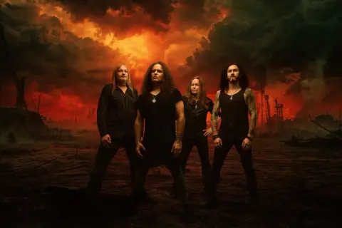 Los miembros de Kreator posan ante un cielo apocalíptico de fuego y humo.