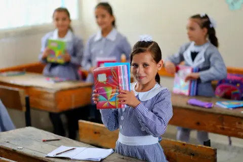 Niña sonriente con cuadernos coloridos en una escuela de Ámsterdam.