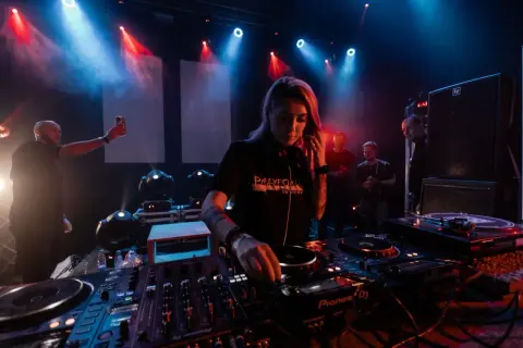 DJ Nusha que es, concentrada en la mesa de mezclas, rodeada de luces y público.