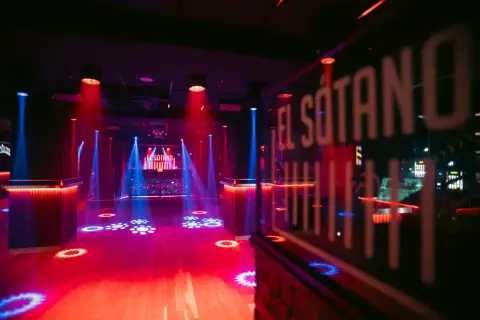 El Sótano, un club techno con luces rojas y azules, pista de baile vacía y DJ listo para la acción.