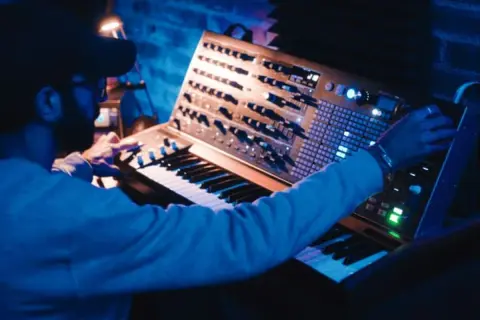 Hombre creando una compleja estructura de música electrónica en un sintetizador modular.