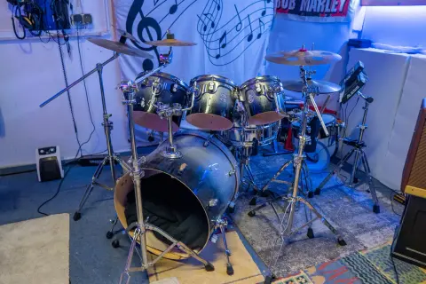 Batería de rock con platillos y un cartel de Bob Marley. ¿Te preguntas dnb que es? Es un género musical.