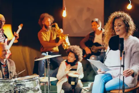 Banda ensayando en estudio. Una cantante lidera, acompañada por saxofón, guitarra, batería y percusión. Sueñan con una gran carrera musical.