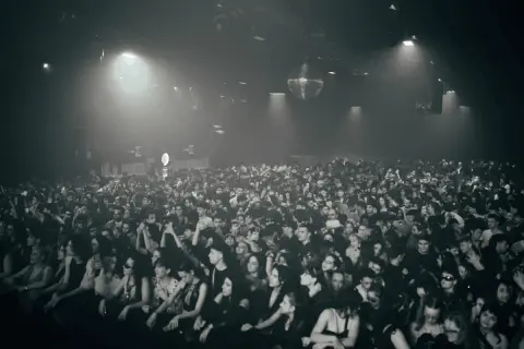 Multitud vibrante disfrutando de la techno musica en un club con luces tenues y una bola de discoteca giratoria.