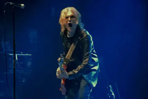 Glenn Hughes, con su banda, desata energía en el escenario. El vocalista y guitarrista, con su icónica melena rubia, grita al público mientras toca su instrumento.
