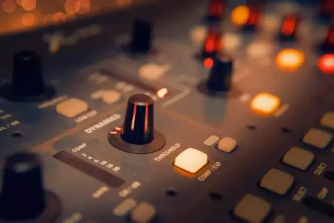 Perillas y botones iluminados en una consola de sonido, creando una atmósfera de mezcla de música.