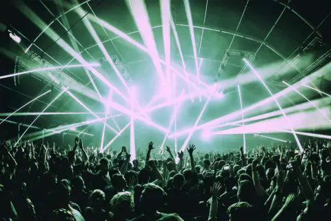 Una multitud celebra bajo un espectáculo de luces láser, un momento cumbre en la historia de la música electrónica.