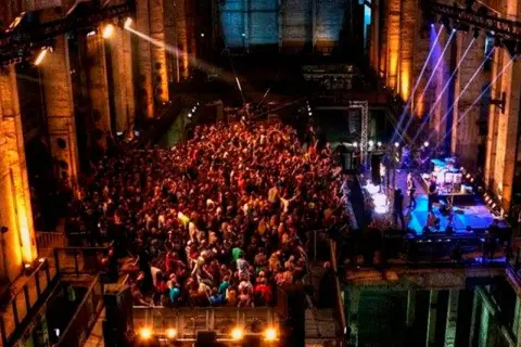 Multitud bailando en un club nocturno con luces de colores, como un **berghain simulator**.