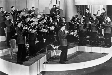 Una big band de jazz en pleno concierto, con músicos tocando trompetas, trombones, saxofones y contrabajo. ¡Pura energía musical!