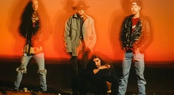 Los miembros de Alice in Chains posan con un fondo naranja vibrante.
