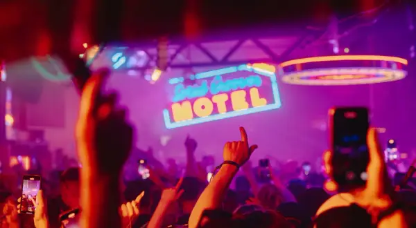 Gente bailando bajo el letrero de neón "Solid Grooves Ibiza Motel" en una fiesta vibrante.