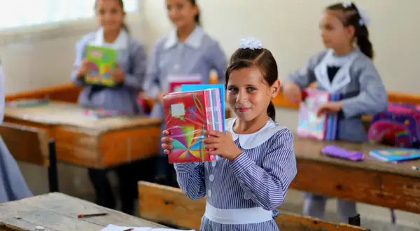 Niña sonriente con cuadernos coloridos en una escuela de Ámsterdam.