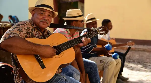 Son cubano cantantes, con guitarras y maracas, crean música alegre bajo el sol.