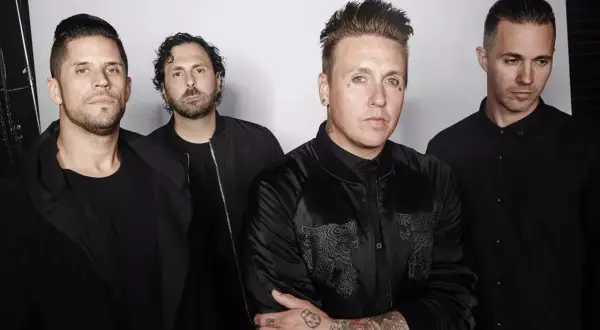 Los miembros de Papa Roach posan juntos, vestidos de negro, con miradas intensas.