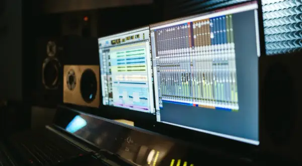 Monitores con software de producción electrónica y mesa de mezclas en un estudio de sonido.
