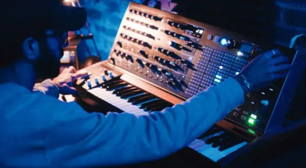 Hombre creando una compleja estructura de música electrónica en un sintetizador modular.