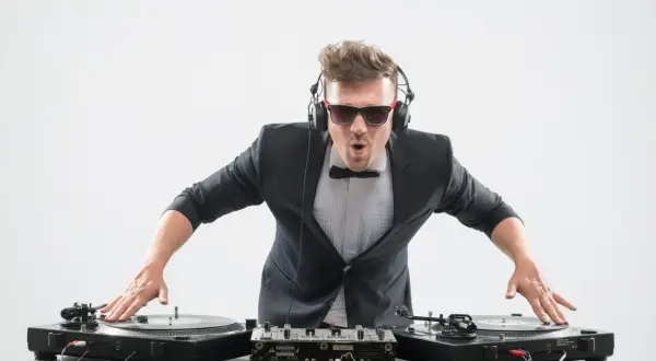 DJ con traje y auriculares, listo para mezclar. Aprende como entrar en una agencia de DJ y triunfar en la música.