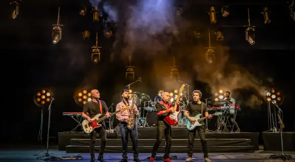Cinco músicos en el escenario, con guitarras, bajo, saxofón y teclados. La banda, como si fueran hermanos, comparte sus opiniones musicales.