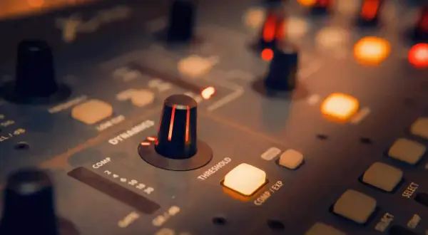 Perillas y botones iluminados en una consola de sonido, creando una atmósfera de mezcla de música.