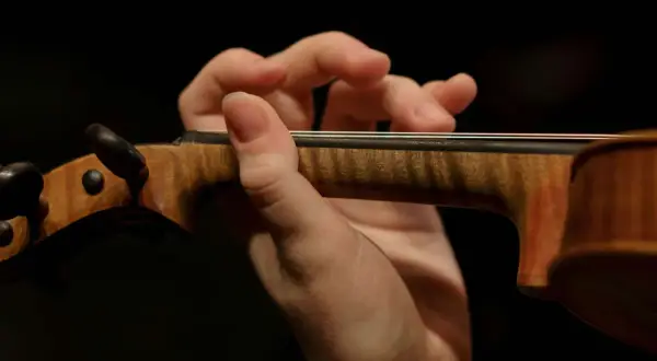 Mano de un violinista tocando con destreza, evocando la maestría de Paganini.