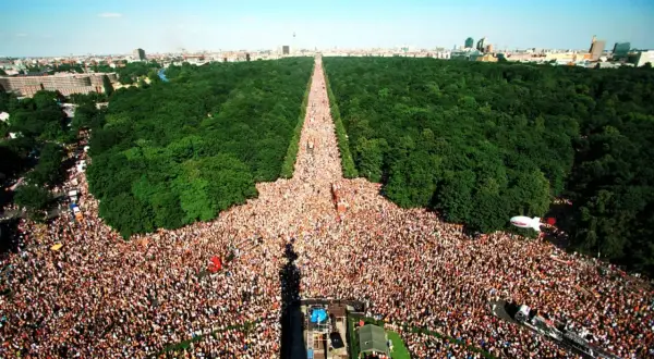 Multitudinaria celebración del Love Parade Berlin, con miles de personas disfrutando en un día soleado.