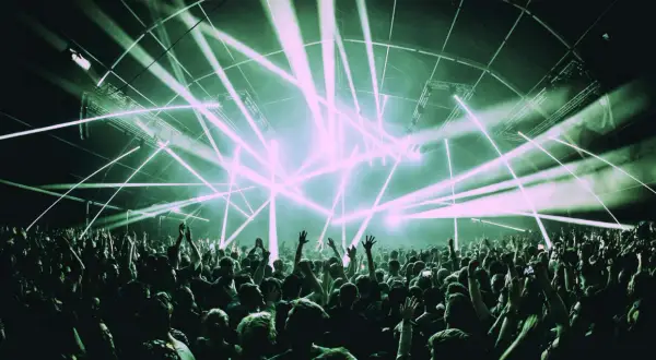 Una multitud celebra bajo un espectáculo de luces láser, un momento cumbre en la historia de la música electrónica.