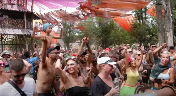 Multitud bailando en un festival psytrance España, con decoraciones coloridas y una estructura de madera.