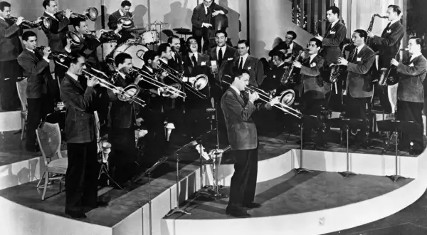 Una big band de jazz en pleno concierto, con músicos tocando trompetas, trombones, saxofones y contrabajo. ¡Pura energía musical!