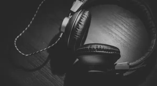 Auriculares negros sobre una superficie de madera, con un juego de luces y sombras que crea un efecto Haas.