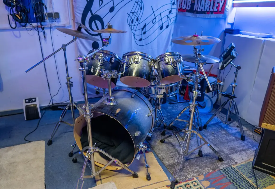 Batería de rock con platillos y un cartel de Bob Marley. ¿Te preguntas dnb que es? Es un género musical.