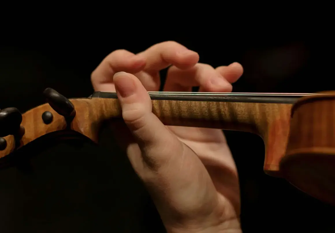 Mano de un violinista tocando con destreza, evocando la maestría de Paganini.