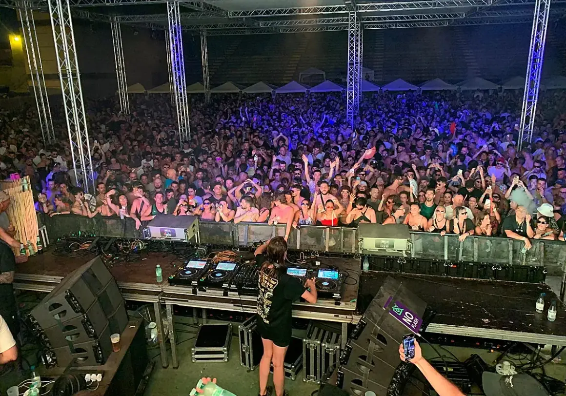 Charlotte de Witte en Málaga, una multitud vibrante baila al ritmo de la música electrónica bajo luces de neón.